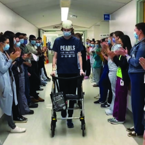 Todd being applauded by hospital staff as he walks the hallway during his recovery